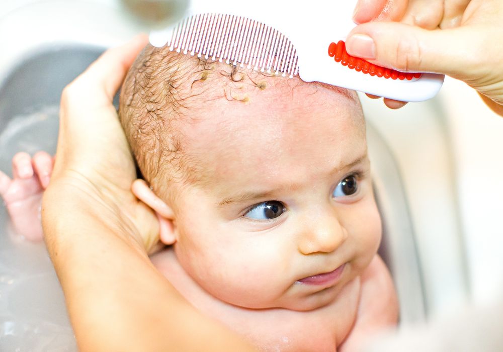 A baby getting their hair brushed in the bath