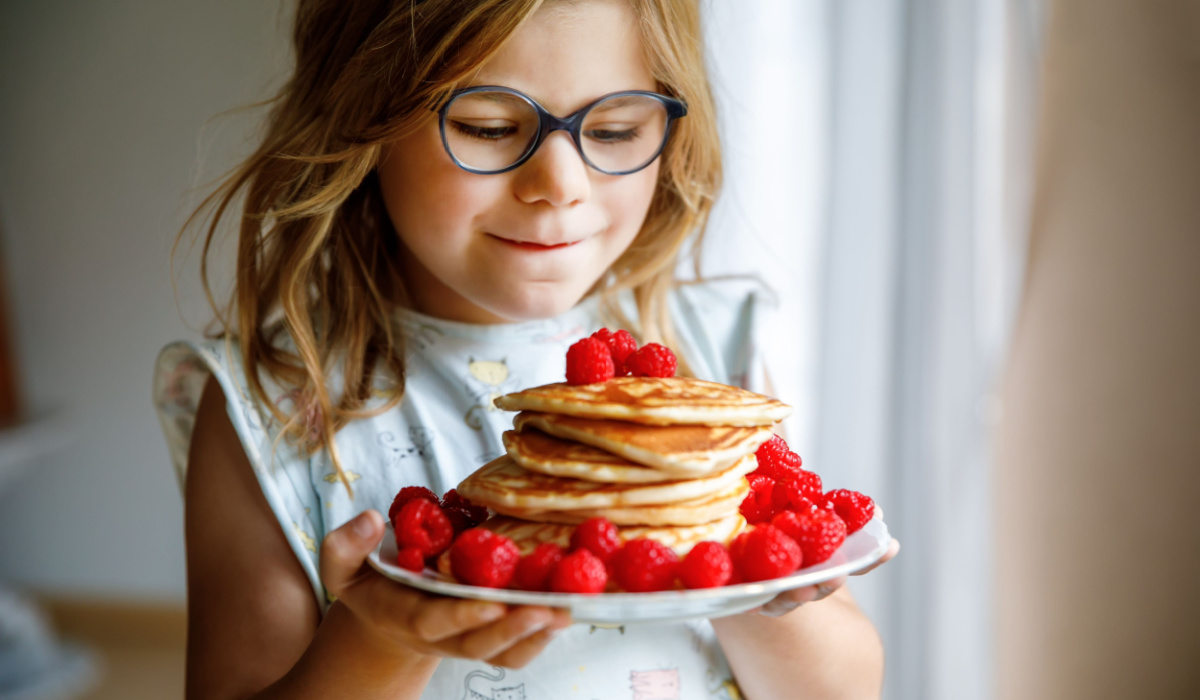 Little girl holding a plate of pancakes
