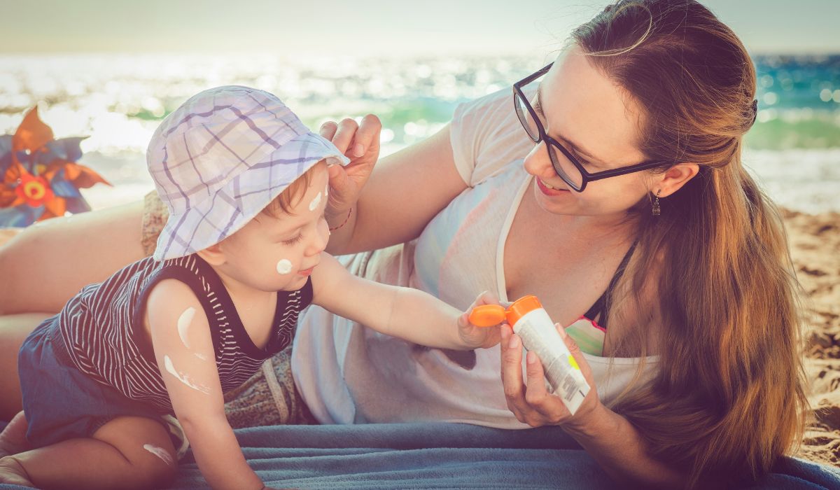 Mum applying suncream to her baby at the beach