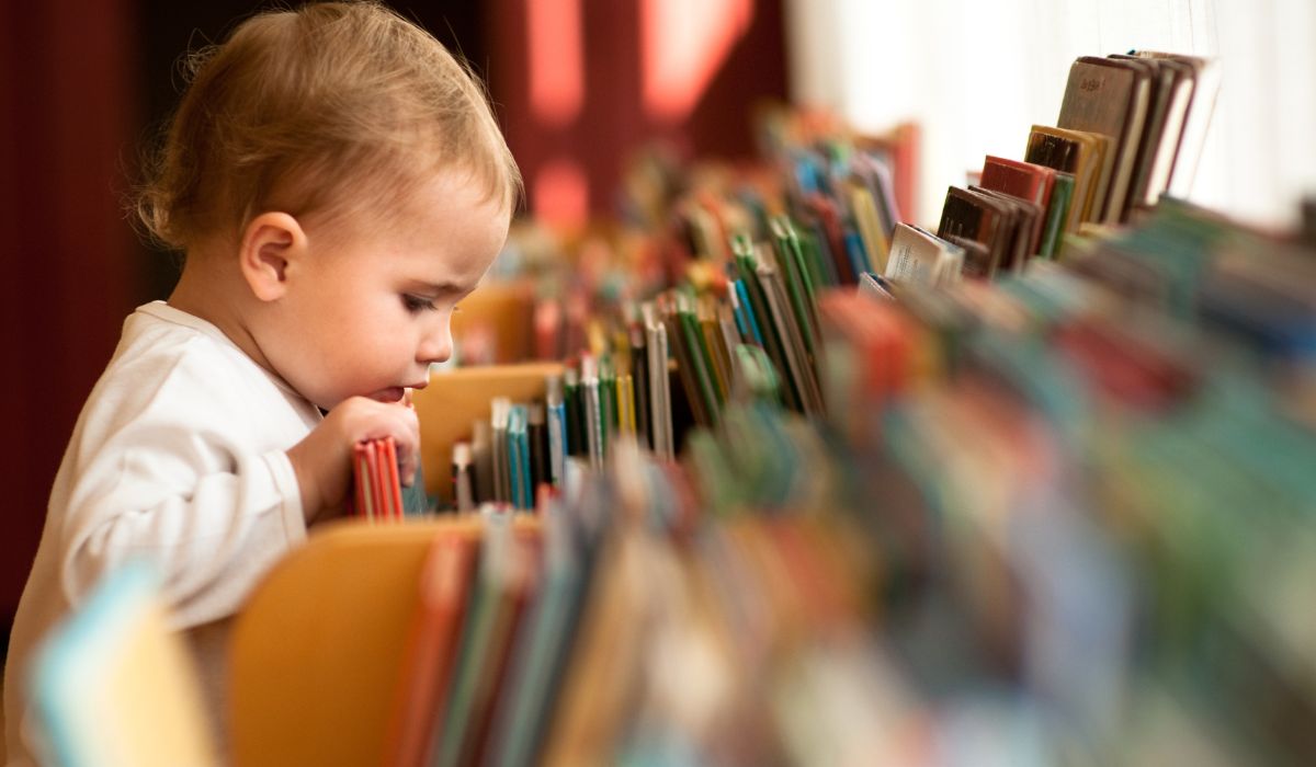 Toddler looking at books on a bookcase