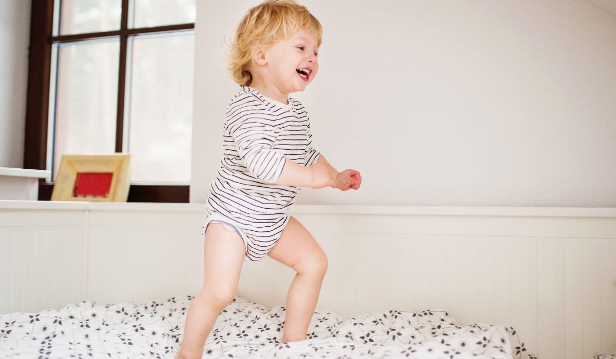 Toddler laughing as they jump on bed