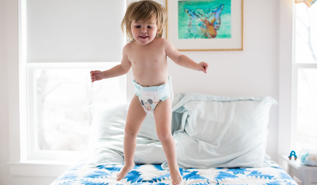 Toddler in nappy jumping on bed