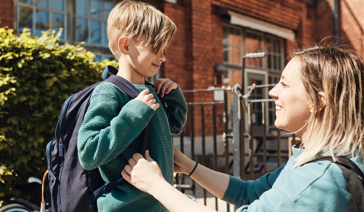 Mum waving son off on first day of school