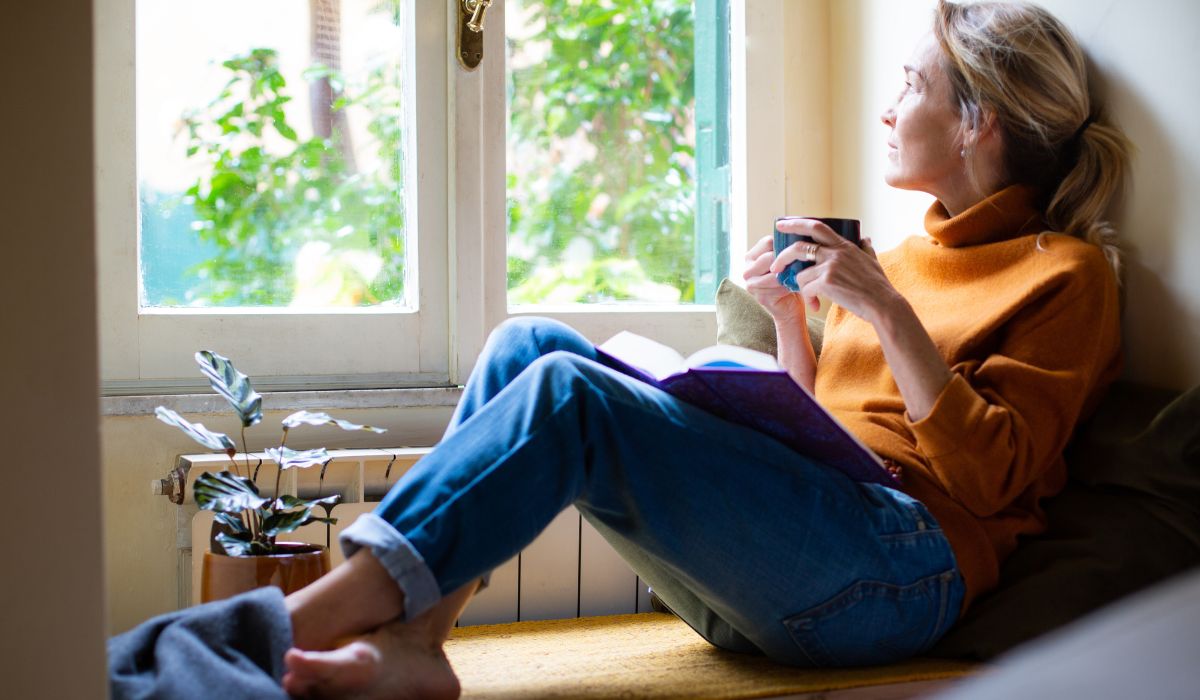 Woman sipping tea in denim and jumper in Autumn