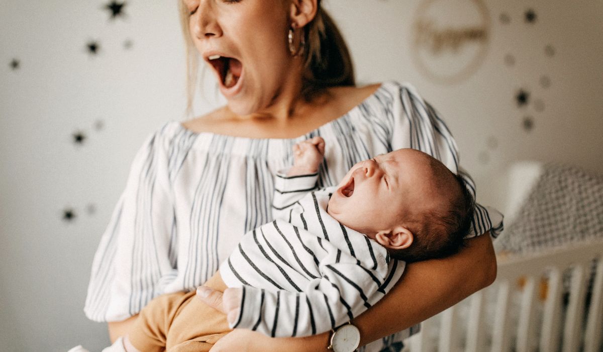 Yawning mother holding yawning baby