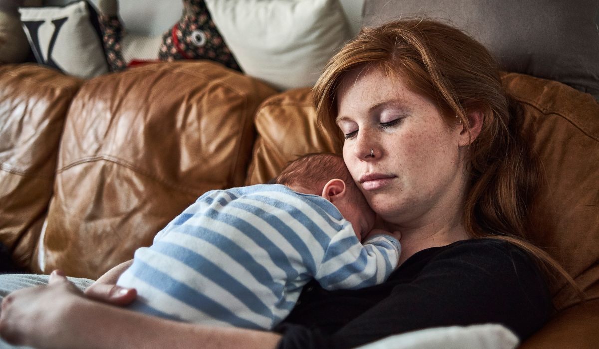 Tired mother holding her sleeping newborn