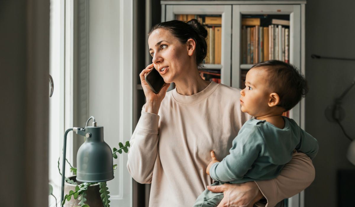 Mum on her phone at home holding her baby