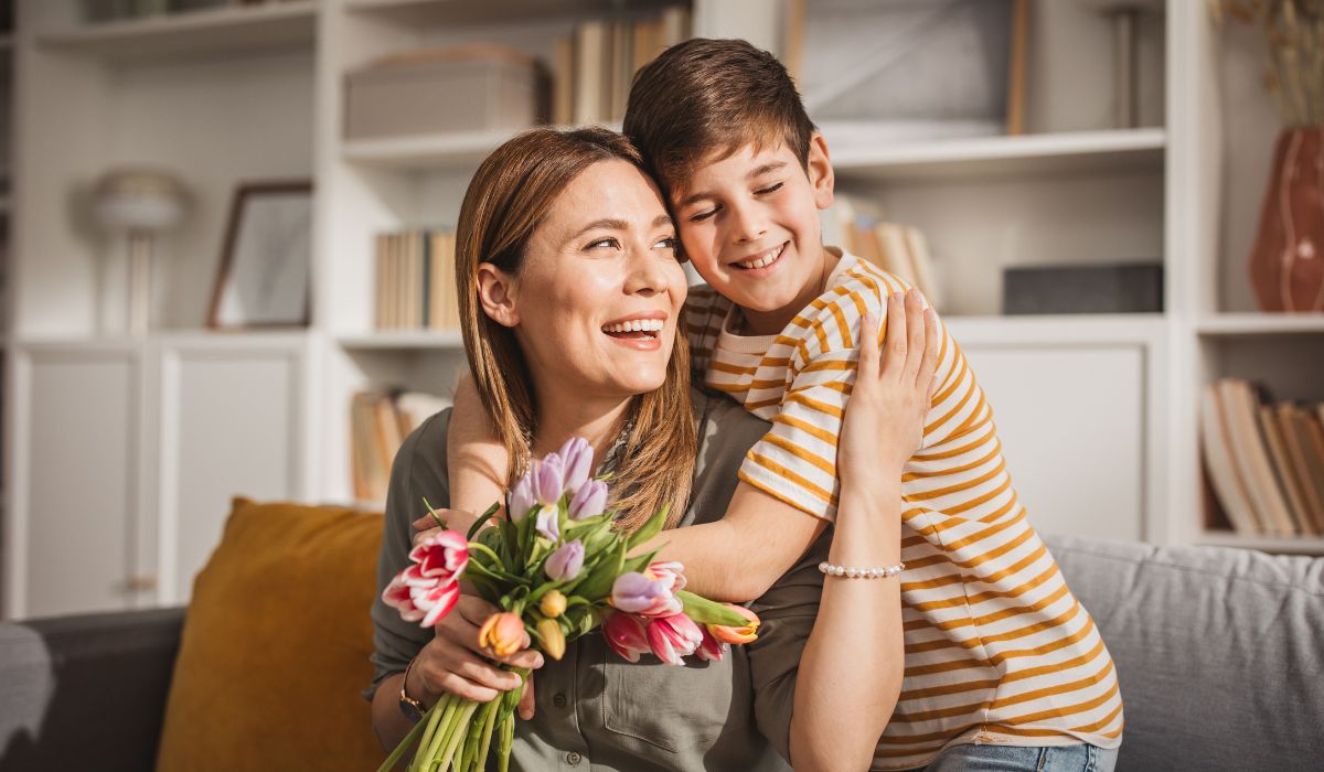 Son giving his mum flowers and a hug