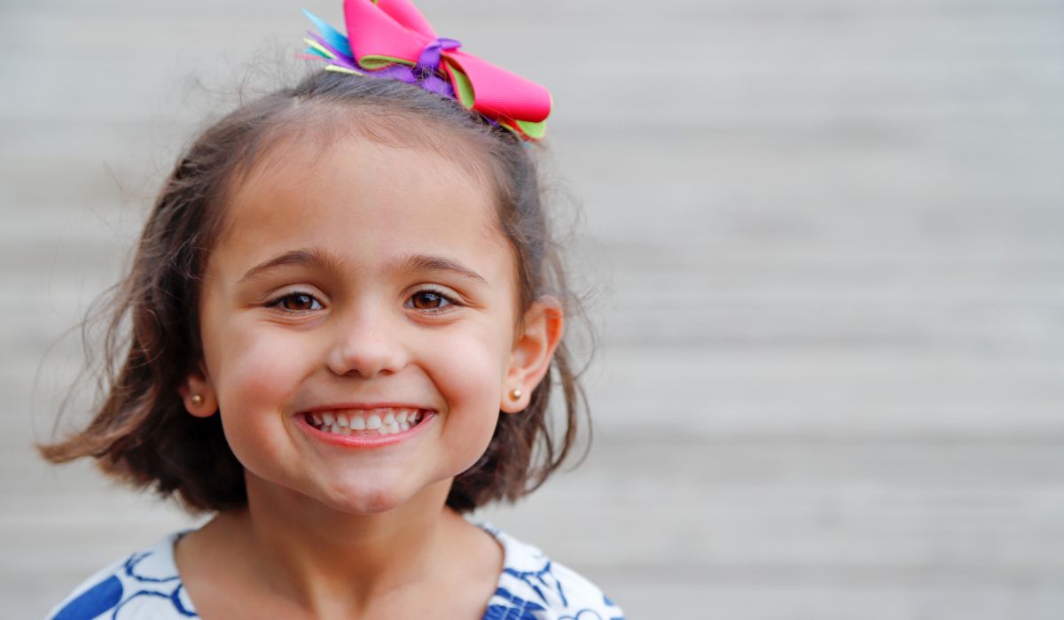 Happy little girl with bow and earrings