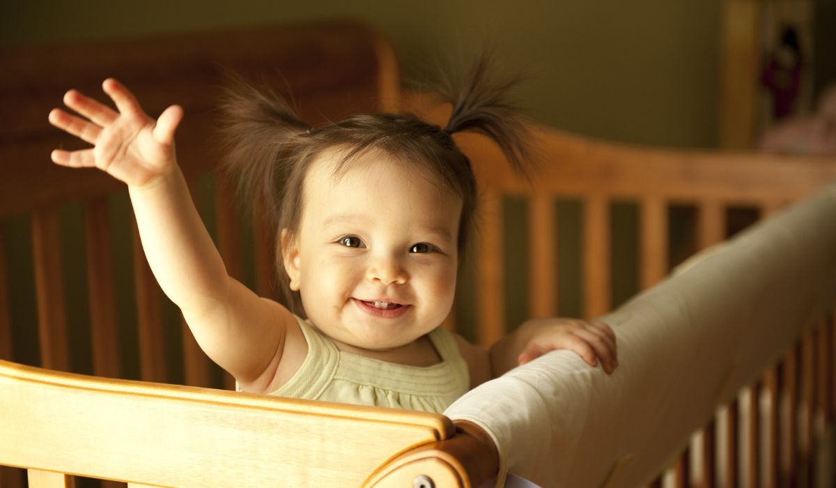 Little waving girl in cot
