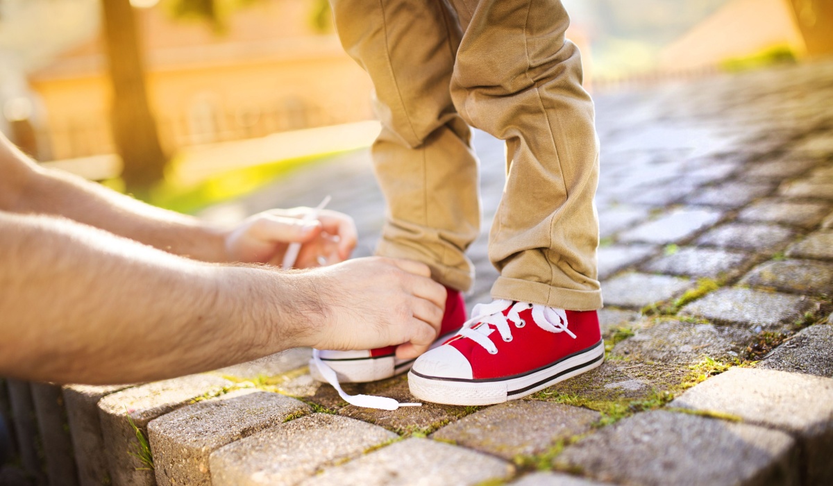 Dad tying son's shoe lace.