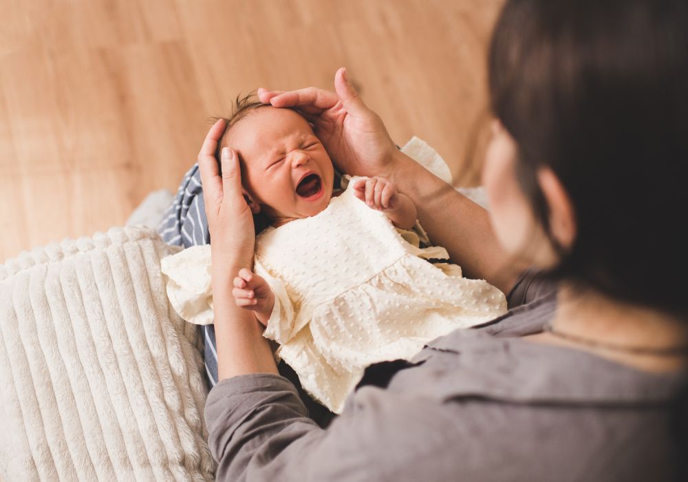 baby crying on mother's lap