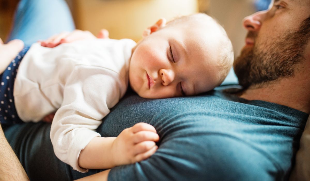 Father lying with daughter on chest