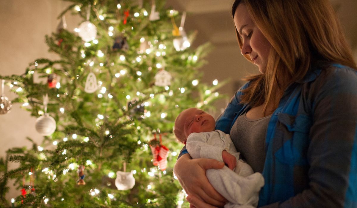 Mother holding her baby in front of a Christmas Tree