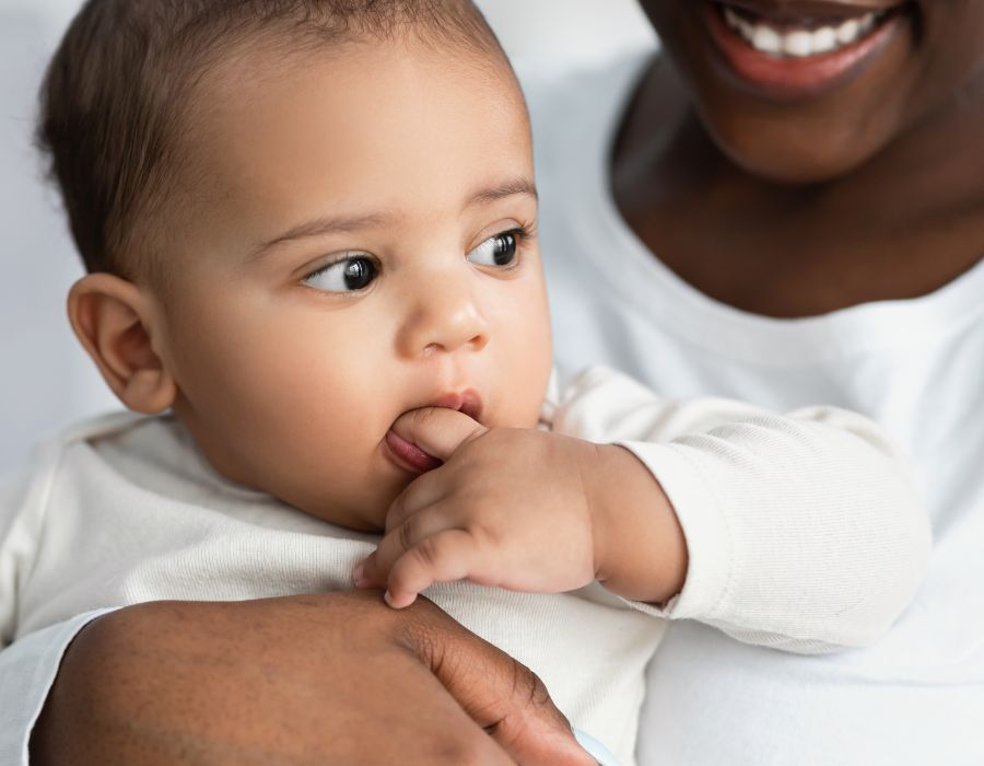 Mother holding baby chewing on finger