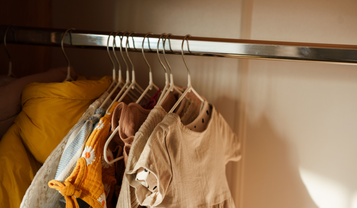 Children's clothes hanging on rack in wardrobe