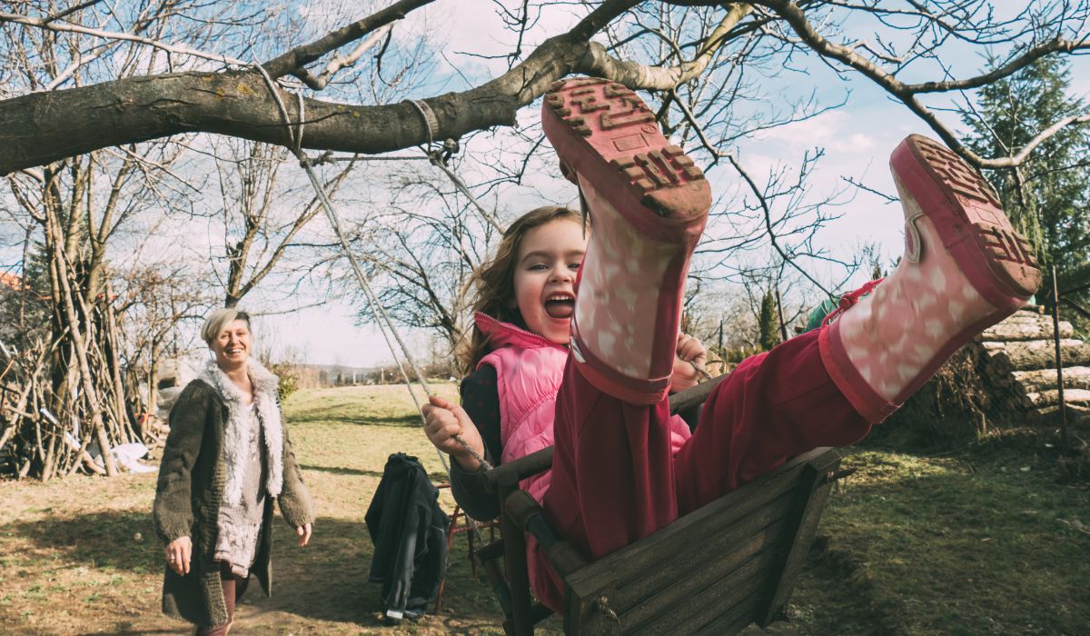 Mother pushing daughter on swing