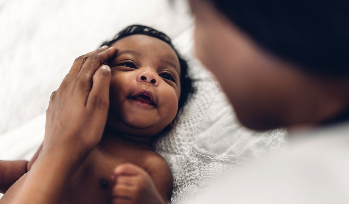 Newborn baby smiling up at mother