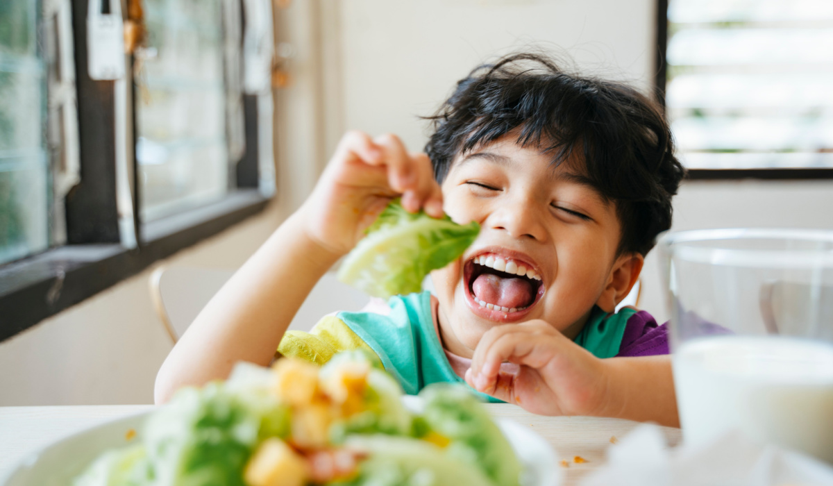 Little boy happy and eating salad