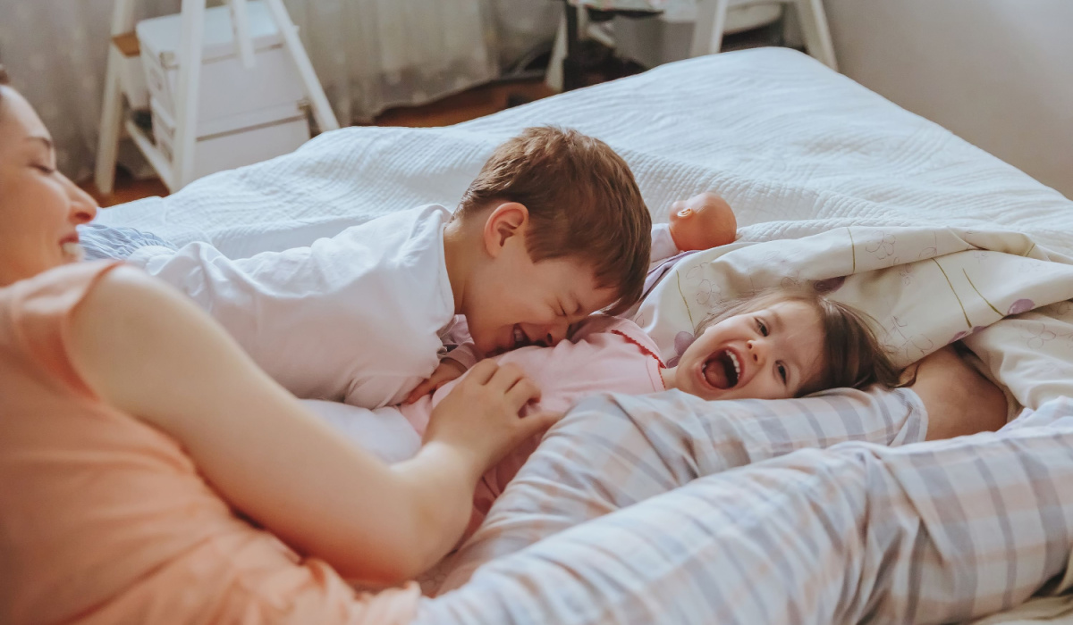 Mum tickling two children on the bed
