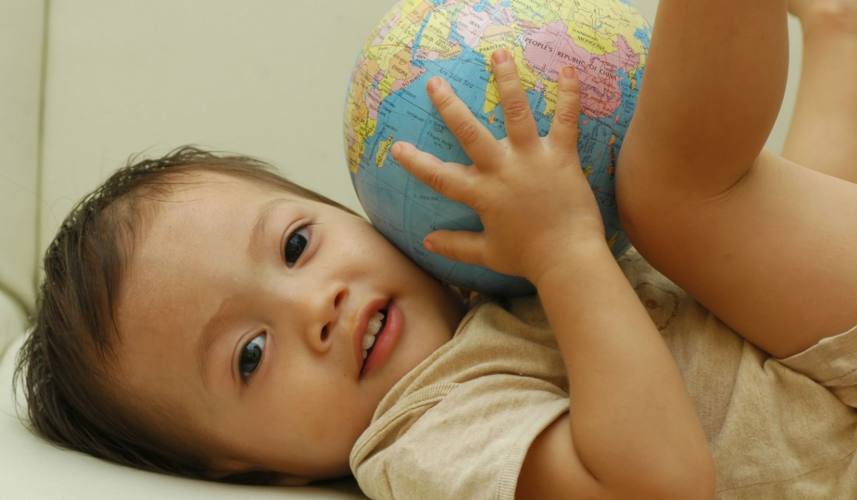 Baby boy holding ball shaped like a globe