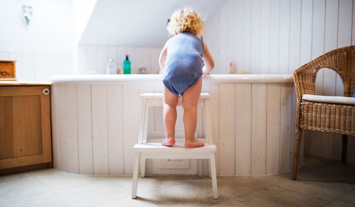 Toddler leaning over bath