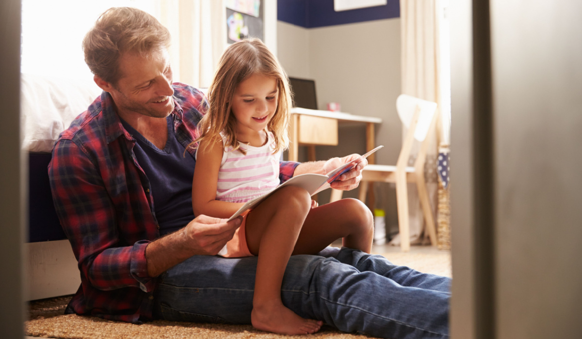 Father reading book to young daughter