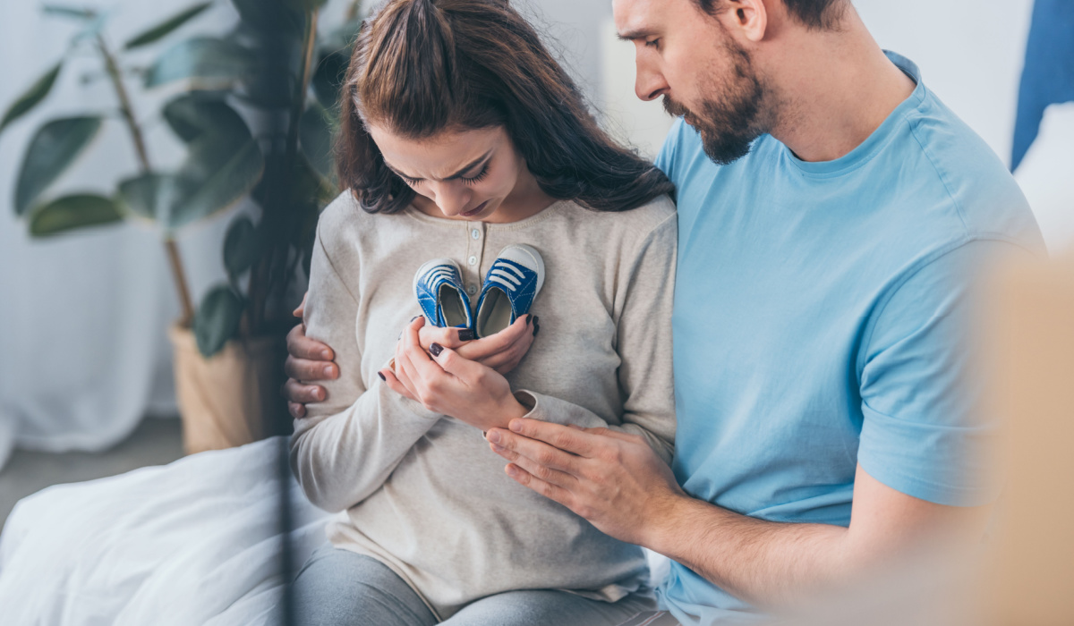 Grieving parents holding a pair of infant shoes