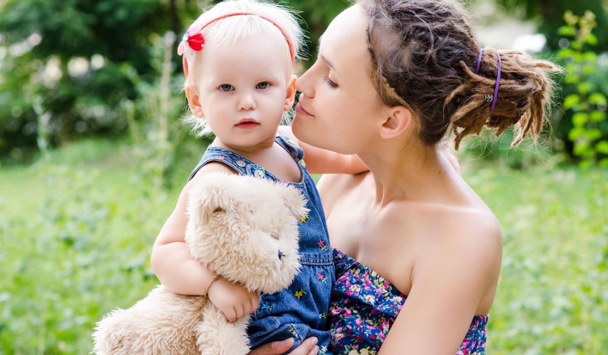 Mother holding baby daughter in field of flowers