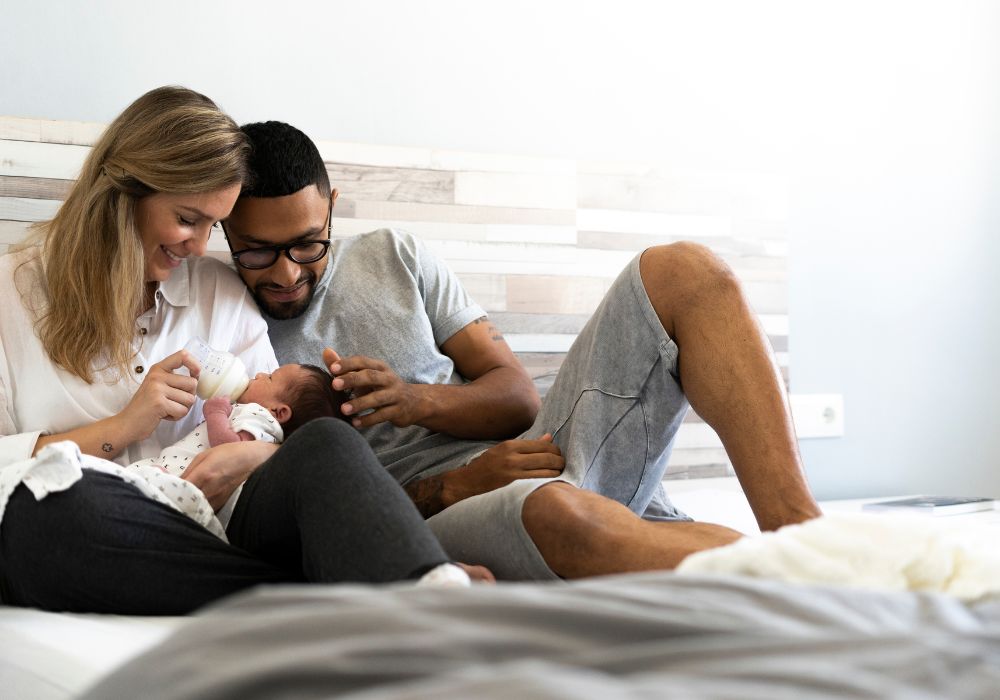 Parents feeding baby on bed