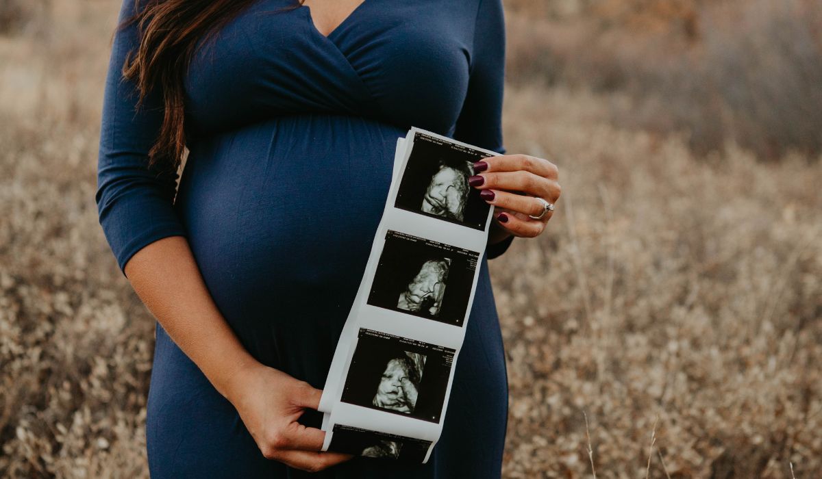Pregnant woman holding ultrasound pictures