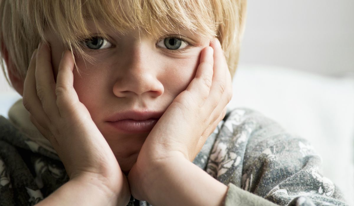 Upset boy with face in his hands