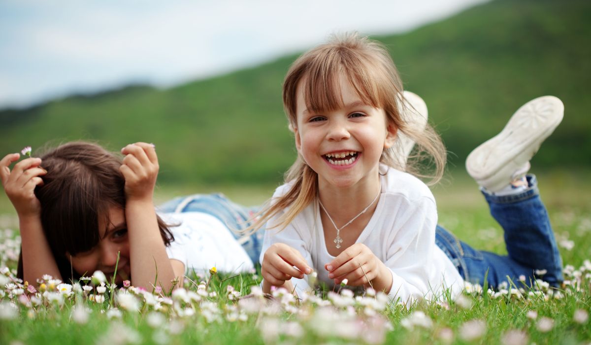 Smiling little girls lying in field of flowers