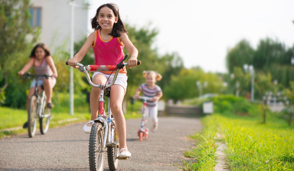 Girls riding on bikes and scooters outside