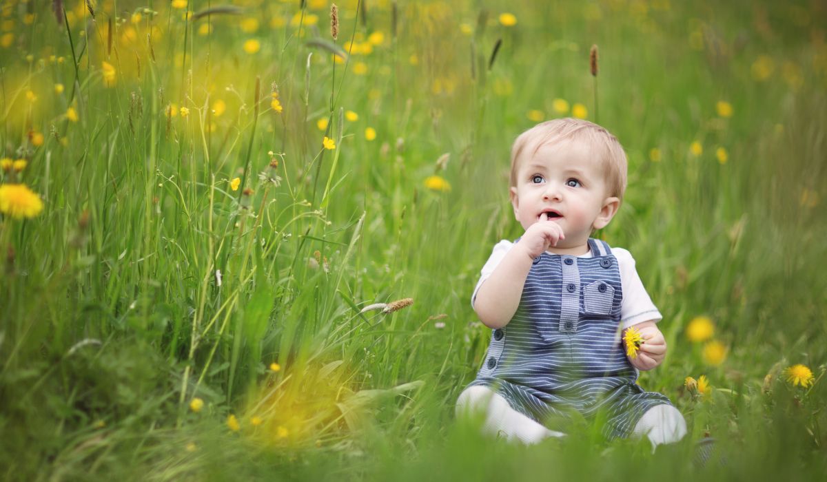 Baby sitting in a field in April