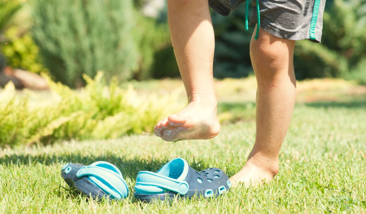 Child playing on grass with clog shoes