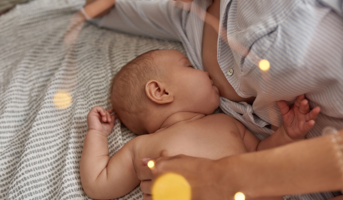 baby breastfeeding in bed with mother