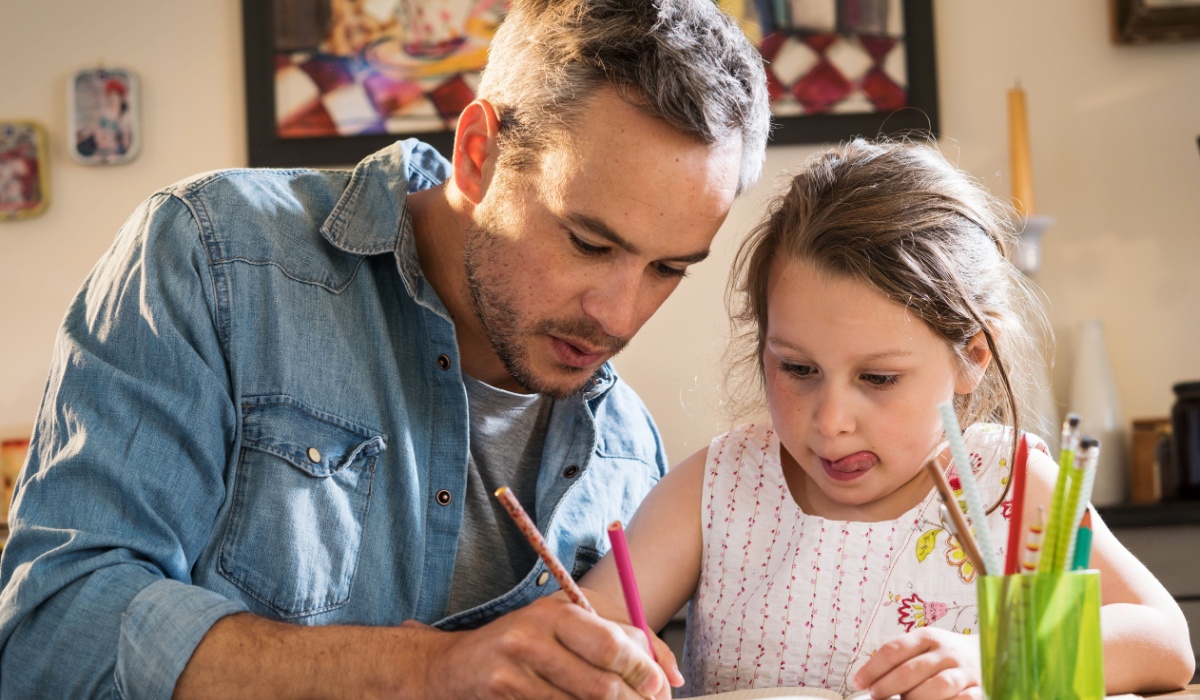 Father doing and daughter doing homework