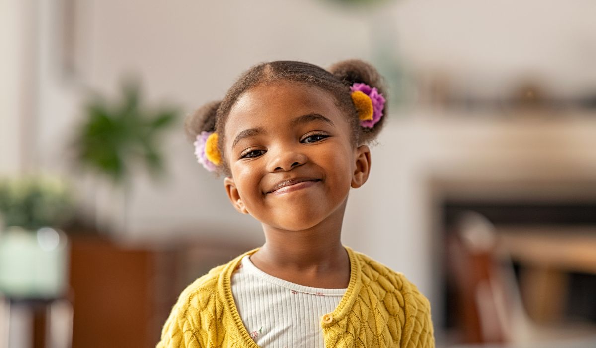 Smiling cute little girl with two pony tails looking at camera.