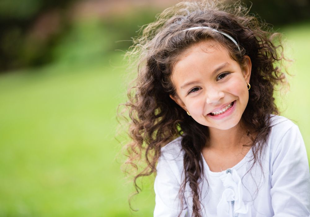 Sweet little girl outdoors with curly hair in the wind