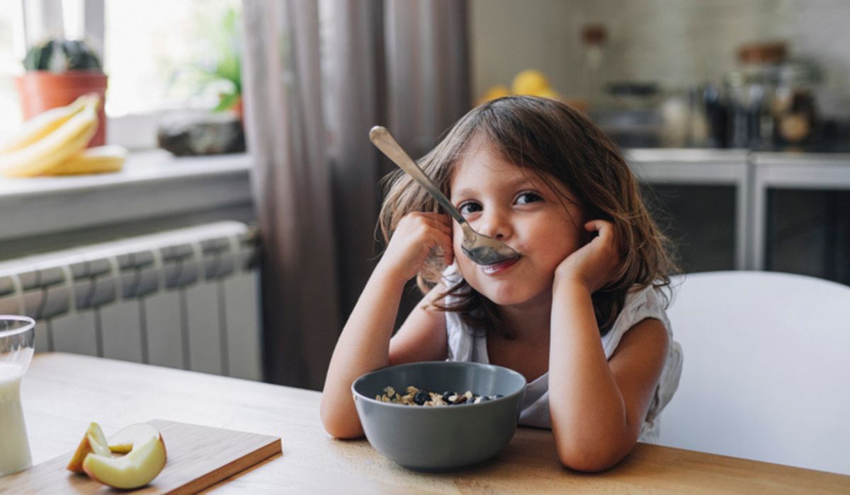 Girl with a spoon in her mouth eating cereal