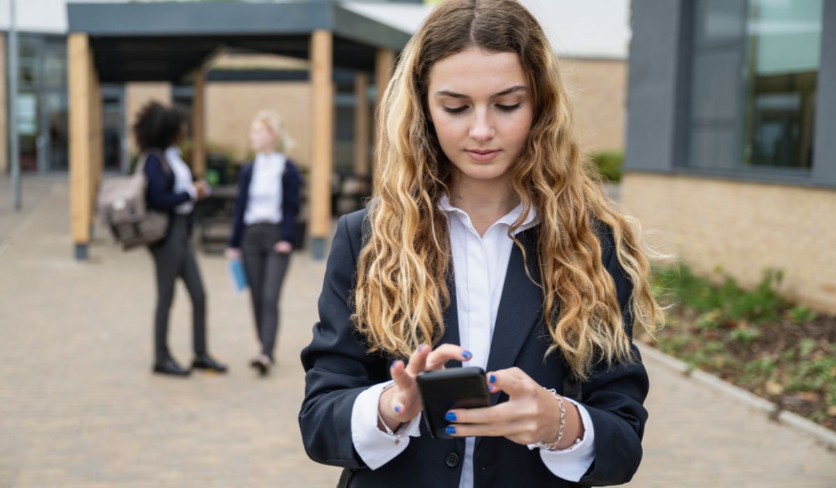 Teenage girl wearing school uniform looking at phone
