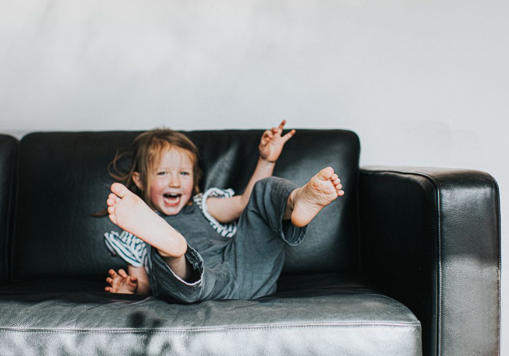 Little girl smiling and jumping on couch