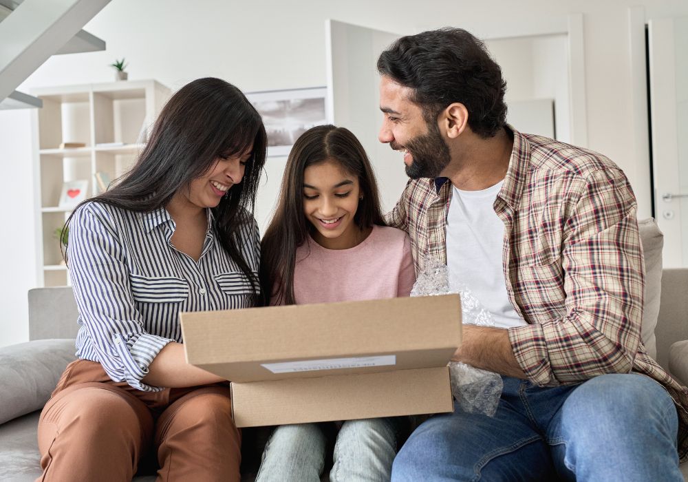 Parents and teenage daughter opening a package while sitting on the couch