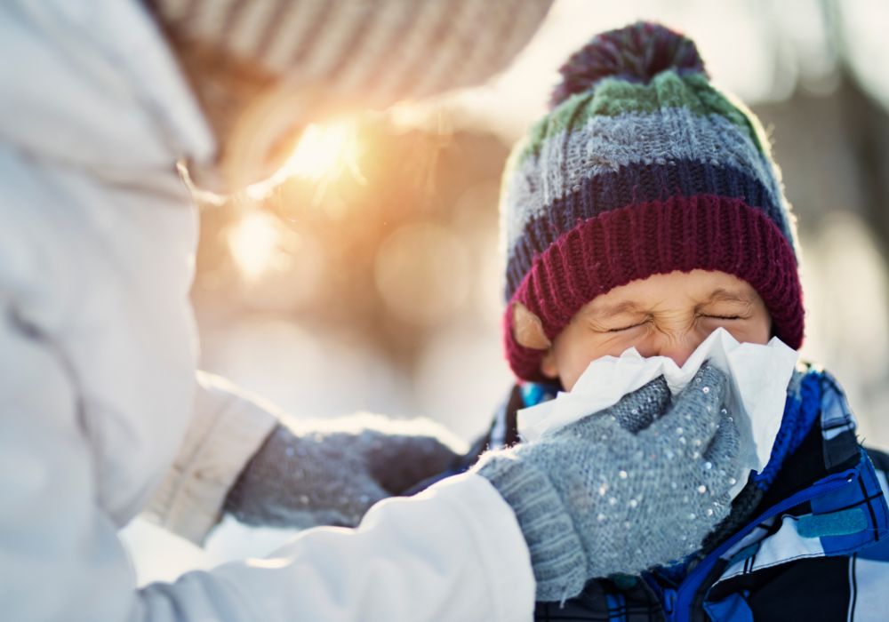 Boy in snow blowing his nose