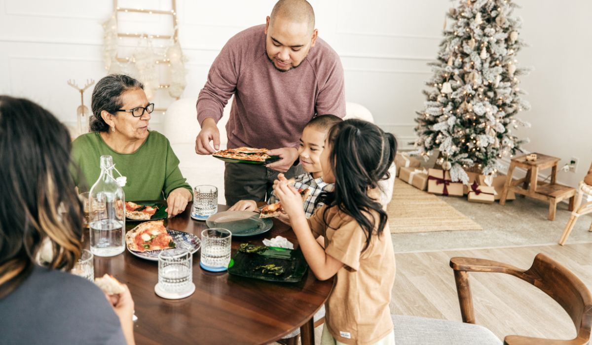 Family eating pizza at table with Christmas tree in the background