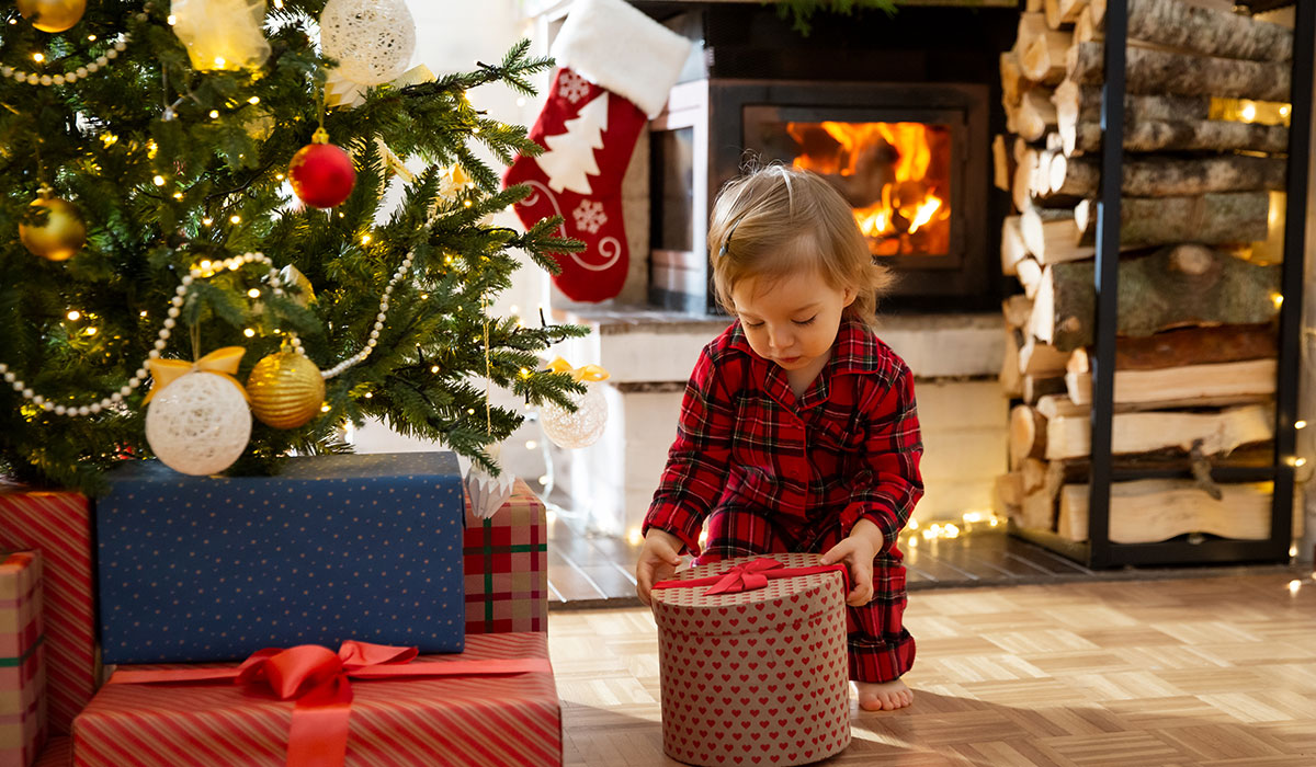 Baby pajamas opening gifts at decorated Christmas tree. Pic: Getty Images