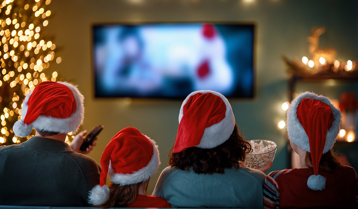 Merry Christmas and Happy New Year. People having fun near tree indoors. Loving family watching holiday movies at home. Mother, father and daughters spending time together.