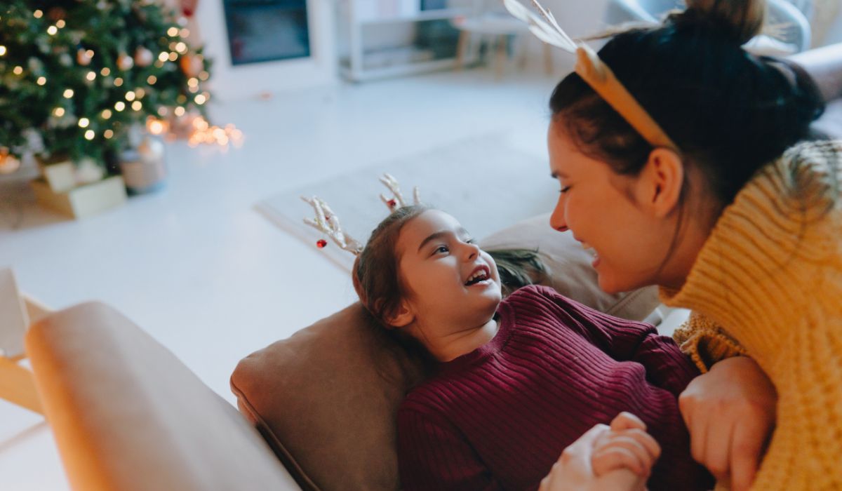 Mother and daughter playing on the couch wearing Christmas antlers