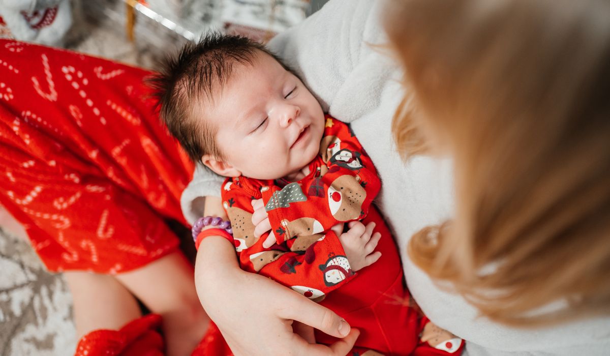 Mother holding newborn wearing Christmas onesie
